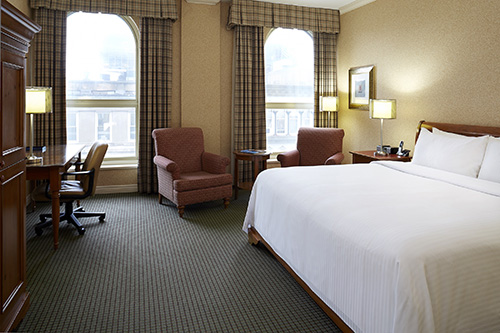 Room at the Barrington Hotel featuring a king-sized bed, a desk, and two armchairs
